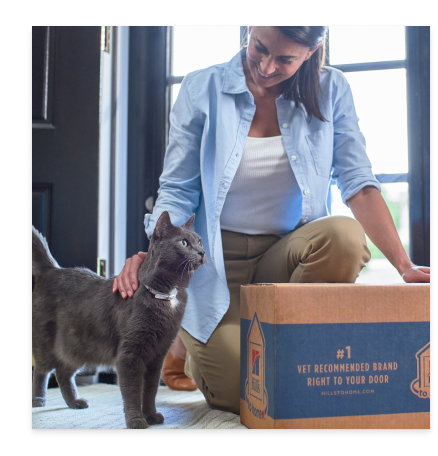 En kvinna med sin svarta lurviga katt och ett paket med Hill's Pet kattfoder